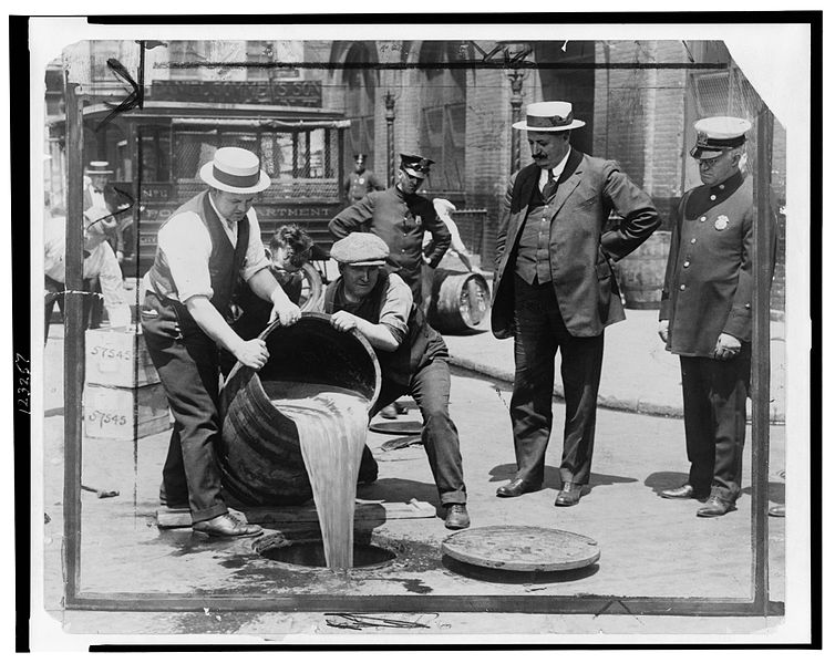 禁酒法時代、違法な酒造所の強制捜査後にニューヨーク市警関係者立会いの下、捜査員によって下水道に廃棄される密造酒。
