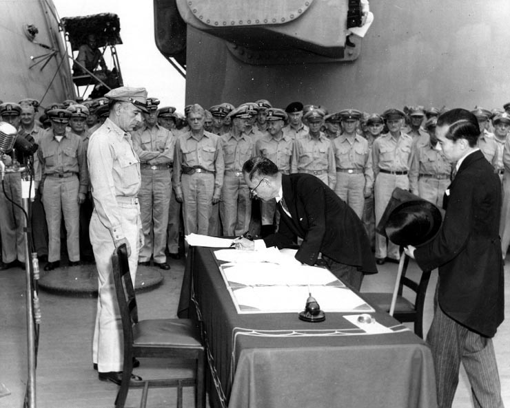1945年9月2日、USSミズーリ艦上でリチャード・サザランド中将が見守る中、降伏文書に署名する重光葵外務大臣、右随行の加瀬俊一